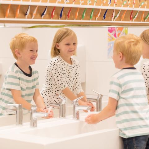 Kinder waschen sich die Hände in der Kita
