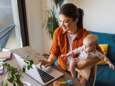 Mutter arbeitet im Home Office mit Baby auf dem Schoß