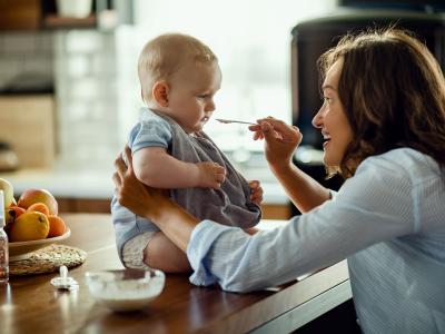 Mutter füttert Baby mit Beikost