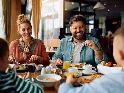 Eltern und Kinder sitzen am Tisch und essen