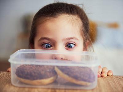Mädchen steht vor Tupperbox mit Dougnats
