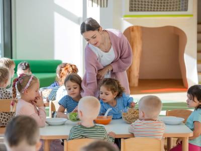 Pädagogische Fachkraft teilt Kindern Essen aus