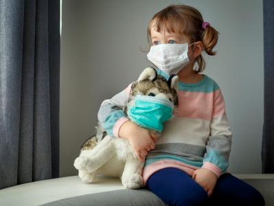 Kind und Kuscheltier mit Mundschutz in der Kita