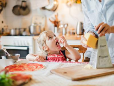 Kind hilft beim kochen und isst Käse
