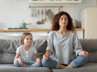Kitakind sitzt mit Mutter auf dem Sofa und macht Atemübung