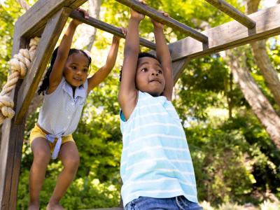 Kindergartenkinder hangeln sich am Klettergerüst des Kindergartens entlang