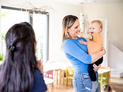 Kita-Leitung und Mutter mit Kind auf dem Arm