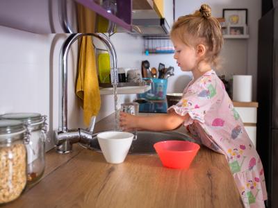 Kind-füllt-Wasserglas-in-der-küche-auf