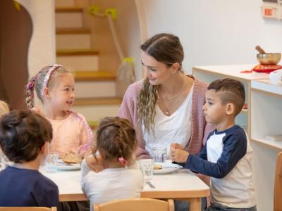 Erzieherin-begleitet-Kinder-bei-der-Brotzeit-am-Tisch