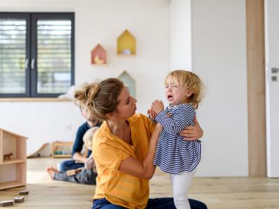 Mädchen weint in der Kita Erzieherin tröstet