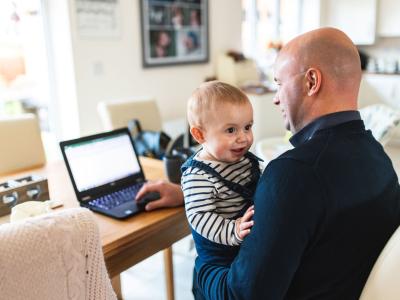 Vater recherchiert Termine im Internet mit Kind auf dem Schoß