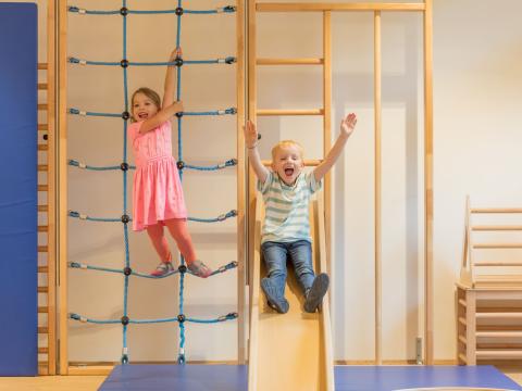Kinder klettern und rutschen im Bewegungsraum