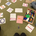 Das Bild zeigt Buchstaben auf Papier und verdeutlicht den Themenabschnitt „Vorschulerziehung im Kindergarten als wichtiges Qualitätsmerkmal der Wichtel Akademie München“.