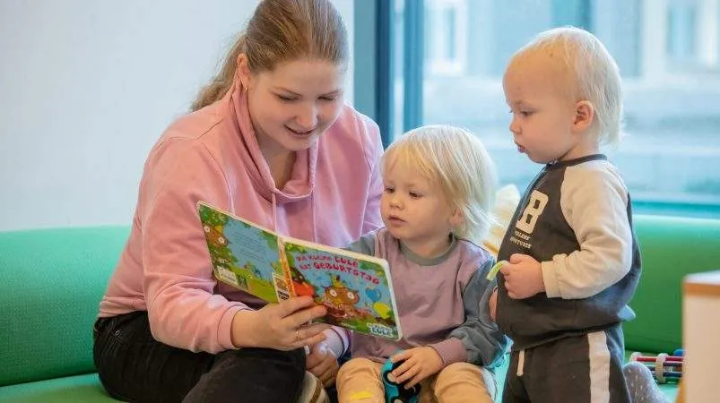 Gute Erzieherin liest ein Buch mit Kind